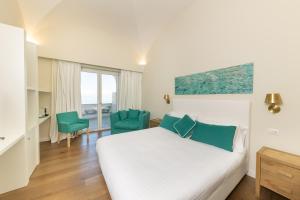 a bedroom with a bed and two green chairs at Casa Dani Capri in Capri