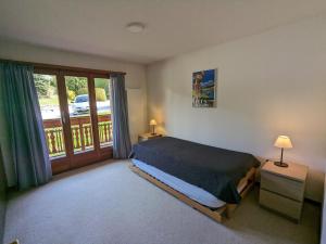 Un dormitorio con una cama y un balcón. en Beau Vallon 04, en Crans-Montana