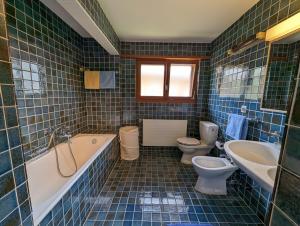 een badkamer met 2 toiletten, een bad en een wastafel bij Beau Vallon 04 in Crans-Montana
