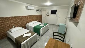 a hotel room with two beds and a table and a television at Pousada Panorâmica in Aracaju
