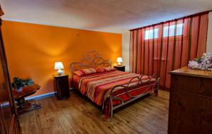 ein Schlafzimmer mit einem Bett mit einer orangefarbenen Wand in der Unterkunft La Mimosa - Bike Friendly Home in Rosignano Solvay