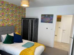 Un dormitorio con una cama con una manta amarilla. en Contemporary & Homely 2 Bed Apartment 10 mins walk to Addenbrookes & Papworth hospitals & Bio Medical Campus, en Trumpington