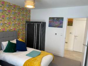 a bedroom with a bed with a yellow blanket on it at Exquisite & Contemporary 2 Bed Apartment w Parking 10 mins walk to Papworth, Addenbrookes hospitals & Bio Medical Campus in Trumpington
