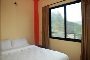 een slaapkamer met een bed en een groot raam bij Panorama Guest House in Nagarkot