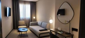 a living room with a couch and a mirror at Silken Ciudad Gijón in Gijón