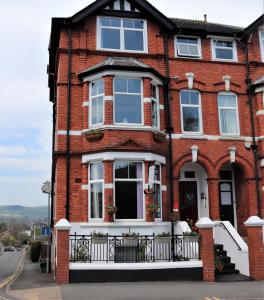 a red brick house with a balcony on a street at Greylands Guest House in Llandrindod Wells