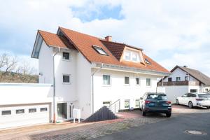 a white house with a red roof at Harmony: Edersee Apartment – Sperrmauer – Lounge in Edersee