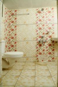 een badkamer met een toilet en bloemen aan de muur bij Bethesda Inn in Cochin