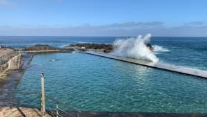 uma onda cai numa piscina no oceano em Apartamentos Tamara em Tacoronte