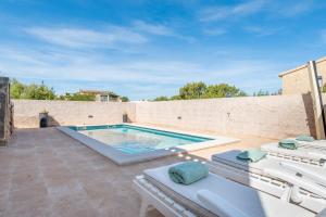 ein Swimmingpool auf einer Terrasse mit zwei Liegen in der Unterkunft Mar i Cel in Colònia de Sant Pere