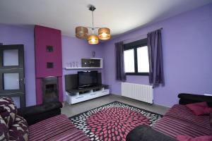 Sala de estar de color púrpura con sofá y TV en Villa Victoria, en Cádiz