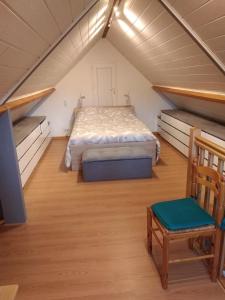 1 dormitorio en el ático con 1 cama y 1 silla en gîte des Caves, en Civray-de-Touraine