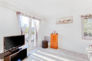 a living room with a flat screen tv and windows at Beau T3 au mont des oiseaux in Hyères
