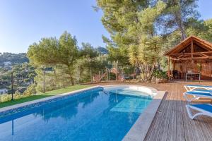 een zwembad met een houten terras en een huis bij Villa enchantée du mont des oiseaux in Hyères