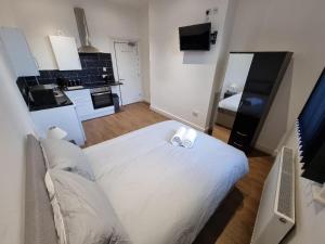 a bedroom with a white bed and a kitchen at Portside Liverpool in Liverpool