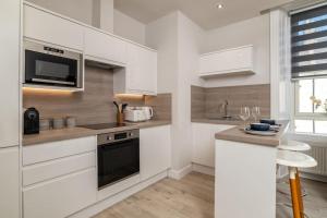 uma cozinha com armários brancos e um forno com placa de fogão em West End @ Netflix @ Newly Built em Aberdeen mais 2 fotografias