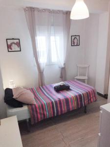 a bedroom with a bed with a colorful blanket at La casita de Pepe - piso compartido in Valencia