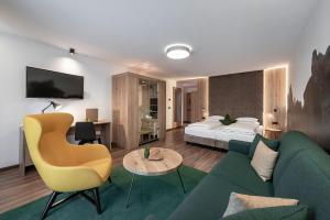 Habitación de hotel con sofá verde y cama en Vitaurina Royal Hotel, en Molini di Tures