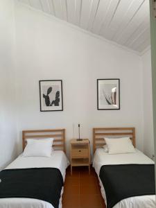 Duas camas num quarto com paredes brancas em Monte do Pereiro em Santiago do Cacém