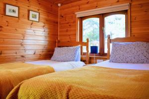 two beds in a room with wooden walls at Secluded Pine Lodge 2 in Wigton
