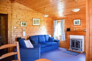 a living room with a blue couch and a fireplace at Secluded Pine Lodge 2 in Wigton