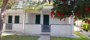 a white house with green shutters and a tree at Ibiscus Beach Village in Follonica