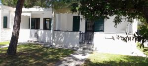 a white house with green shutters and a tree at Ibiscus Beach Village in Follonica