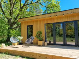 een huis met twee stoelen op een houten terras bij Ale Miejscówka! Całoroczny domek nad jeziorem in Lucień