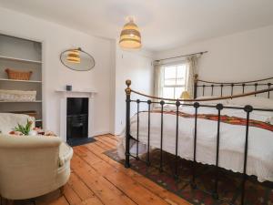 a bedroom with a bed and a chair and a fireplace at Victoria Cottage in Saxmundham