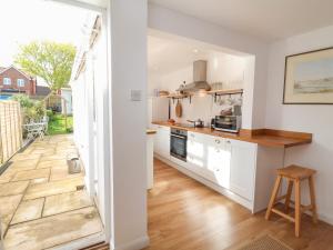 a kitchen with white cabinets and a wooden floor at Victoria Cottage in Saxmundham