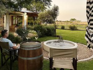 un hombre sentado en una mesa con dos barriles de vino en Olyf guestcottage en Bloemfontein