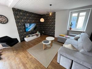 a living room with a couch and a tv at Les gîtes de Madline, Le gîte du prieuré in Saint-Georges-de-Gréhaigne