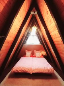 a bed in a wooden attic with a window at Gemütliches Ferienhaus mit sonniger Terrasse Frankenwald nähe Badesee Smart-TV in Lichtenberg