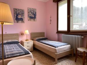 two beds in a room with pink walls at Casa Michela in Crone
