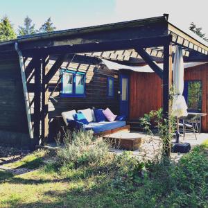 una casa con un sofá azul bajo una pérgola en Tiny House bei Mardorf am Steinhuder Meer, en Rehburg-Loccum