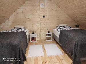 two beds in a room with a wooden wall at Pan Modrzew in Zachełmie