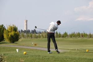 mężczyzna huśtający kijem golfowym na polu golfowym w obiekcie Garda Residence San Vigilio Golf w mieście Pozzolengo