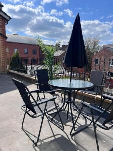 a table and chairs with an umbrella on a patio at The Burton- Free Gated Parking in Manchester