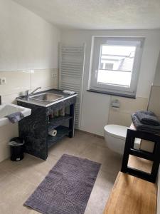 uma casa de banho com um lavatório, um WC e uma janela. em Ferienwohnung *stadtnah* ruhig* modern em Ravensburg