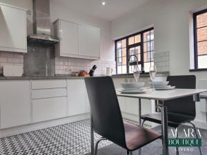 a kitchen with white cabinets and a table and chairs at 3 Floor Townhouse Luxury Living Alara Boutique in Birmingham