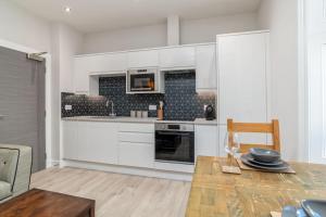 a kitchen with white cabinets and a wooden table at * Ground Floor * The Grove * in Aberdeen