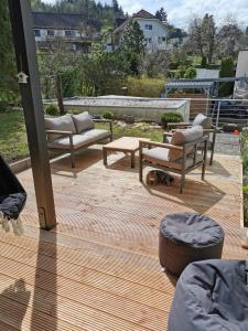 a patio with couches and a dog laying on a wooden deck at Ferienwohnung in Waldrandlage in Nationalpark Schleiden / Eifel in Schleiden