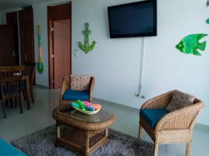 a living room with two chairs and a table and a tv at Apartamento Frente al Mar in Santa Marta