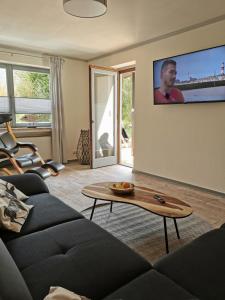 a living room with a couch and a tv on the wall at Ferienwohnung in Waldrandlage in Nationalpark Schleiden / Eifel in Schleiden +82 photos