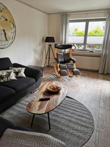 een woonkamer met een bank, een tafel en een stoel bij Ferienwohnung in Waldrandlage in Nationalpark Schleiden / Eifel in Schleiden