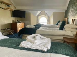 a room with four beds with towels on them at Bryn Noddfa in Morfa Nefyn