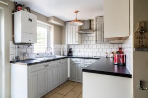 a kitchen with white cabinets and black counter tops at Cosy Nottingham City Centre Townhouse in Nottingham