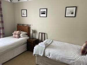 a bedroom with two beds and two pictures on the wall at Bryn Noddfa in Morfa Nefyn