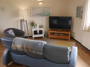 a living room with a blue couch and a flat screen tv at Talehay Cottages in Looe