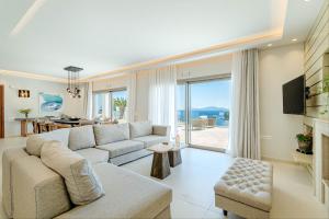 a living room with a white couch and a large window at Kalami Beach - Villa Mara in Kalami